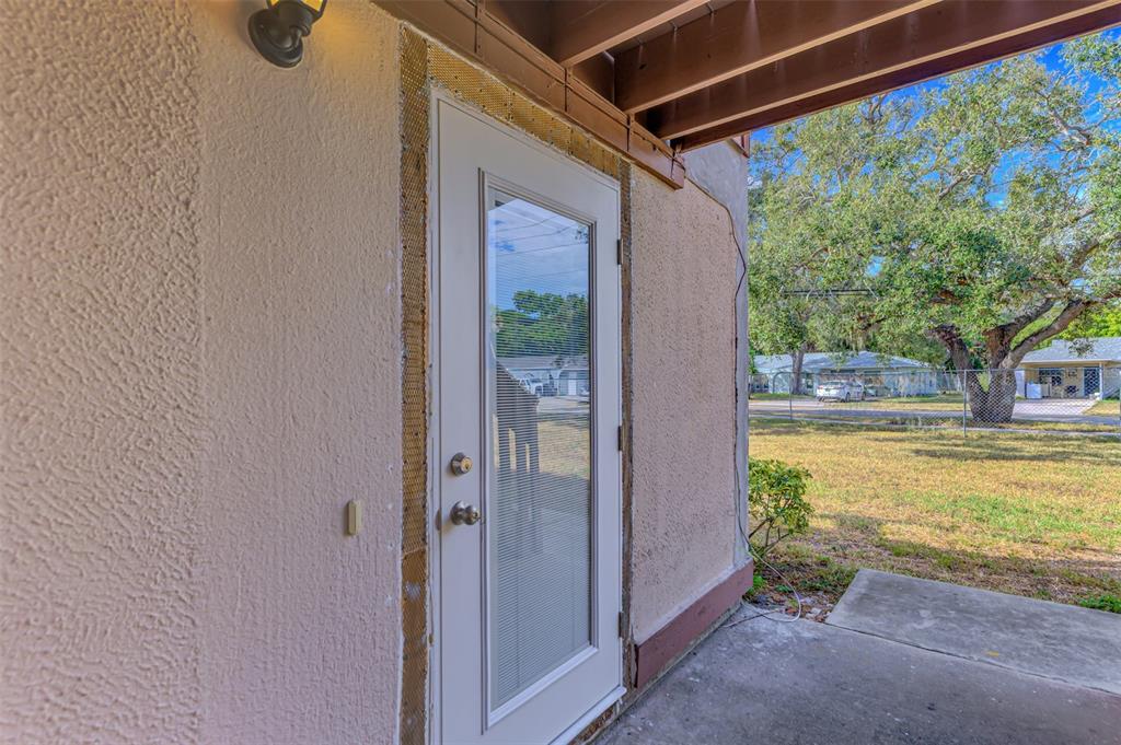A white exterior door with a glass insert is set into a stucco wall — 5026 WATER OAK DRIVE UNIT 102, BRADENTON, FL