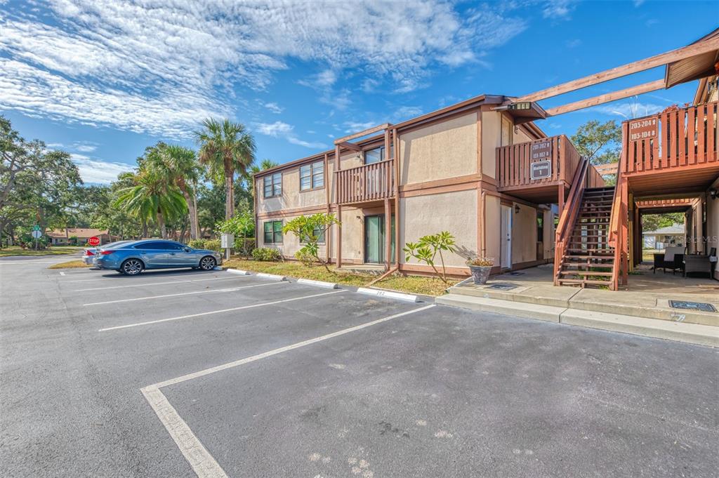 A two-story apartment building with wooden balconies and an outdoor staircase next to a parking lot — 5026 WATER OAK DRIVE UNIT 102, BRADENTON, FL