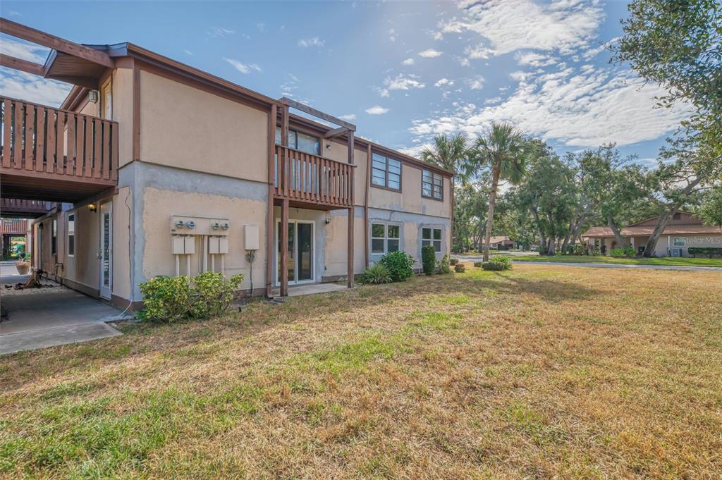 Exterior view of a two-story apartment building with a wooden balcony and a grassy yard — 5026 WATER OAK DRIVE UNIT 102, BRADENTON, FL