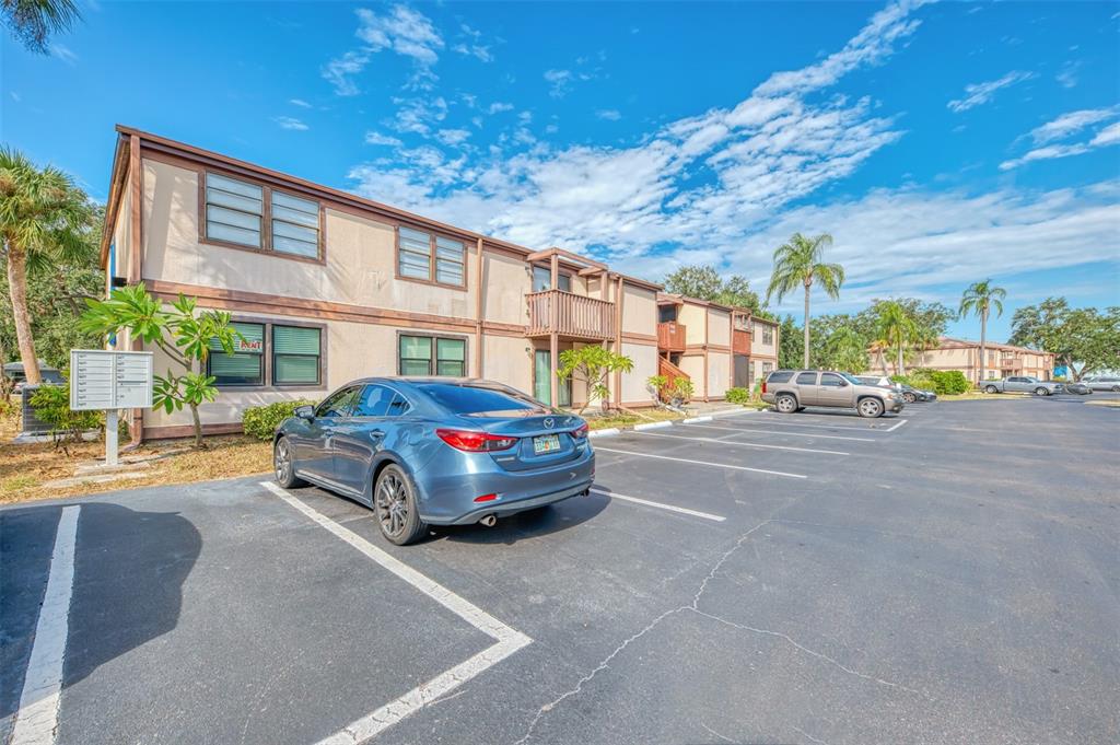 A blue sedan is parked in front of a two-story apartment building with palm trees — 5026 WATER OAK DRIVE UNIT 102, BRADENTON, FL