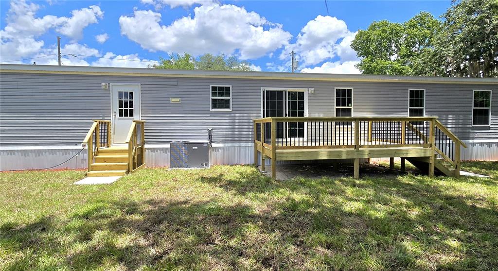 A light gray manufactured home with a wooden porch sits behind a chain-link fence — 659 ALPINE STREET, MASCOTTE, FL
