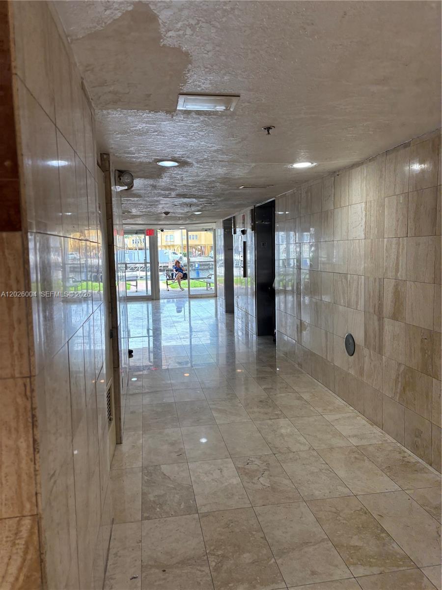 A tiled hallway leads to glass doors opening onto a waterfront patio area — 1800 NW 24th Ave # 314, Miami FL 33125, MIAMI, FL
