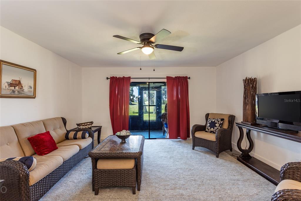 A living room features wicker furniture, a ceiling fan, and sliding glass doors to a patio — 23 OCEAN PALM VILLA DRIVE N, FLAGLER BEACH, FL