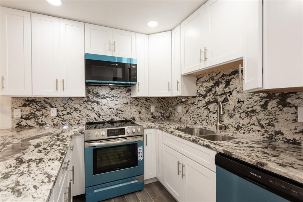 A kitchen features white cabinets, granite countertops, and blue Frigidaire appliances — 23 OCEAN PALM VILLA DRIVE N, FLAGLER BEACH, FL
