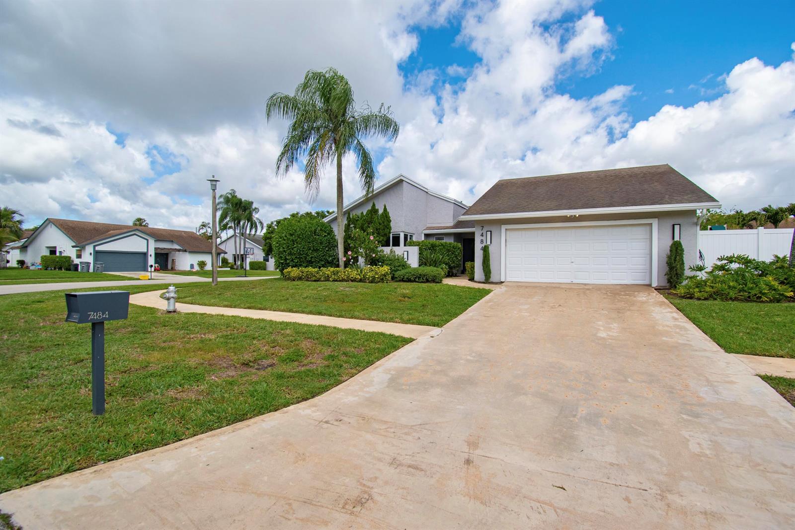 A single-story house with a white garage, a concrete driveway, and a palm tree — 7484 Malibu Crescent, Boca Raton FL 33433, BOCA RATON, FL