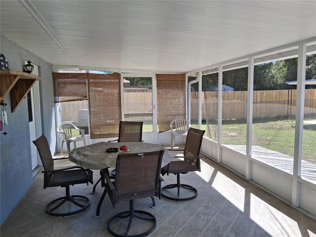 A view from a covered porch overlooking a fenced grassy yard and a large field — 515 BOITNOTT LANE, BUSHNELL, FL
