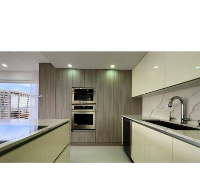 A modern kitchen features light wood cabinetry, white upper cabinets, stainless steel appliances, and marble countertops — 11111 biscayne blvd # 1815, Miami FL 33181, MIAMI, FL