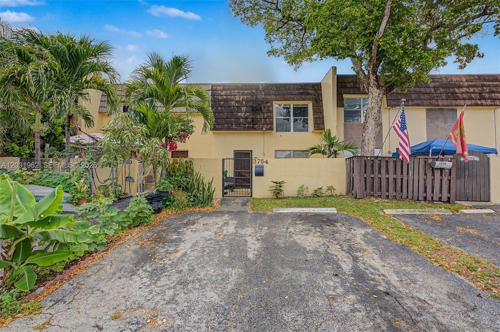 A two-story townhouse exterior features a paved driveway, a gated courtyard, and a brown roof — 3764 SW 60th Ter # 15, Davie FL 33314, DAVIE, FL