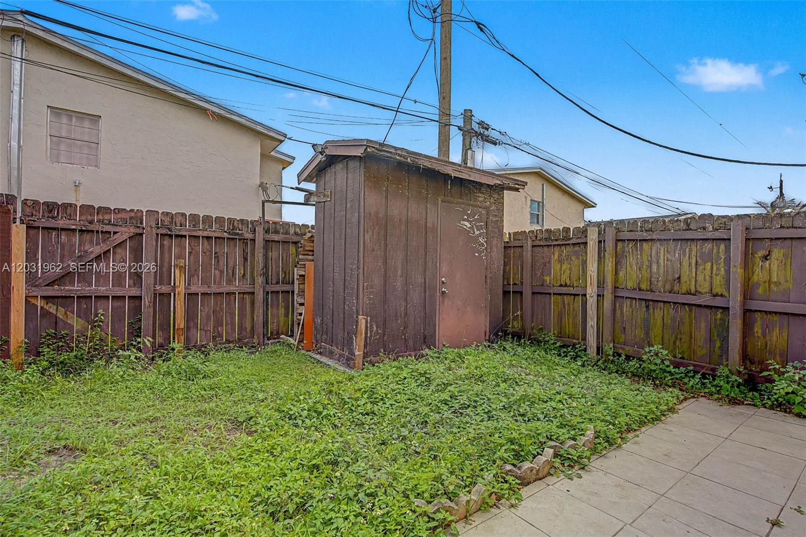 A small wooden shed stands in a backyard enclosed by a weathered wooden fence — 3764 SW 60th Ter # 15, Davie FL 33314, DAVIE, FL