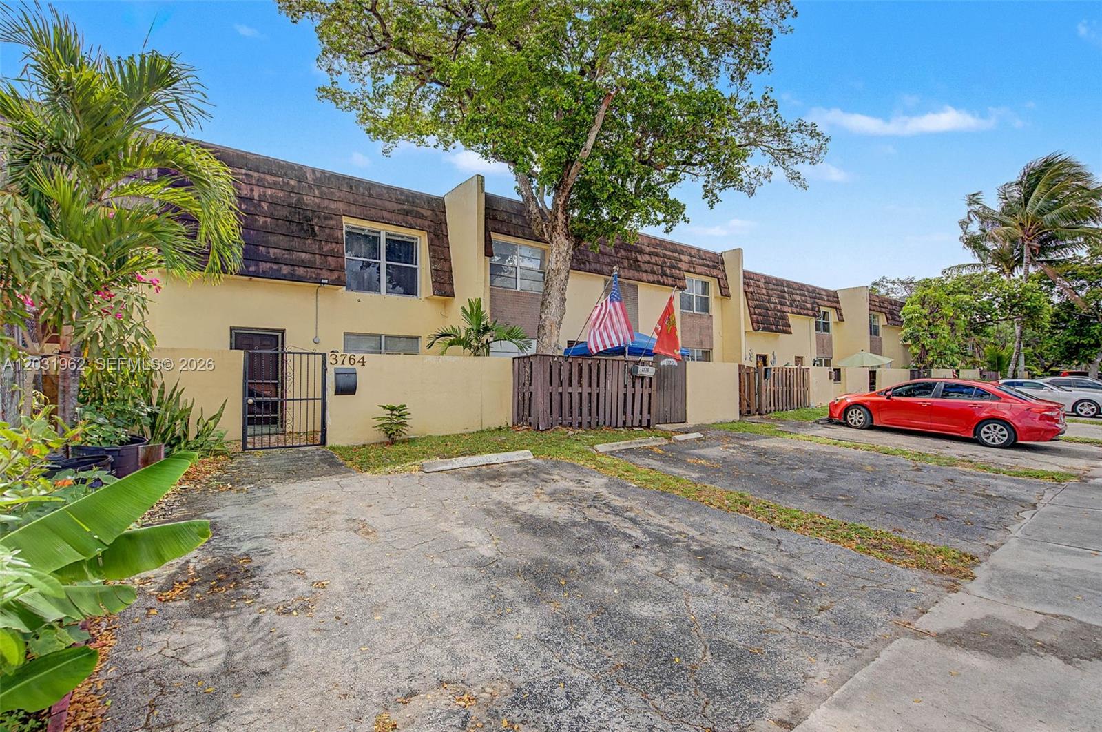 A two-story townhouse exterior features a paved driveway, a small front courtyard, and mature trees — 3764 SW 60th Ter # 15, Davie FL 33314, DAVIE, FL