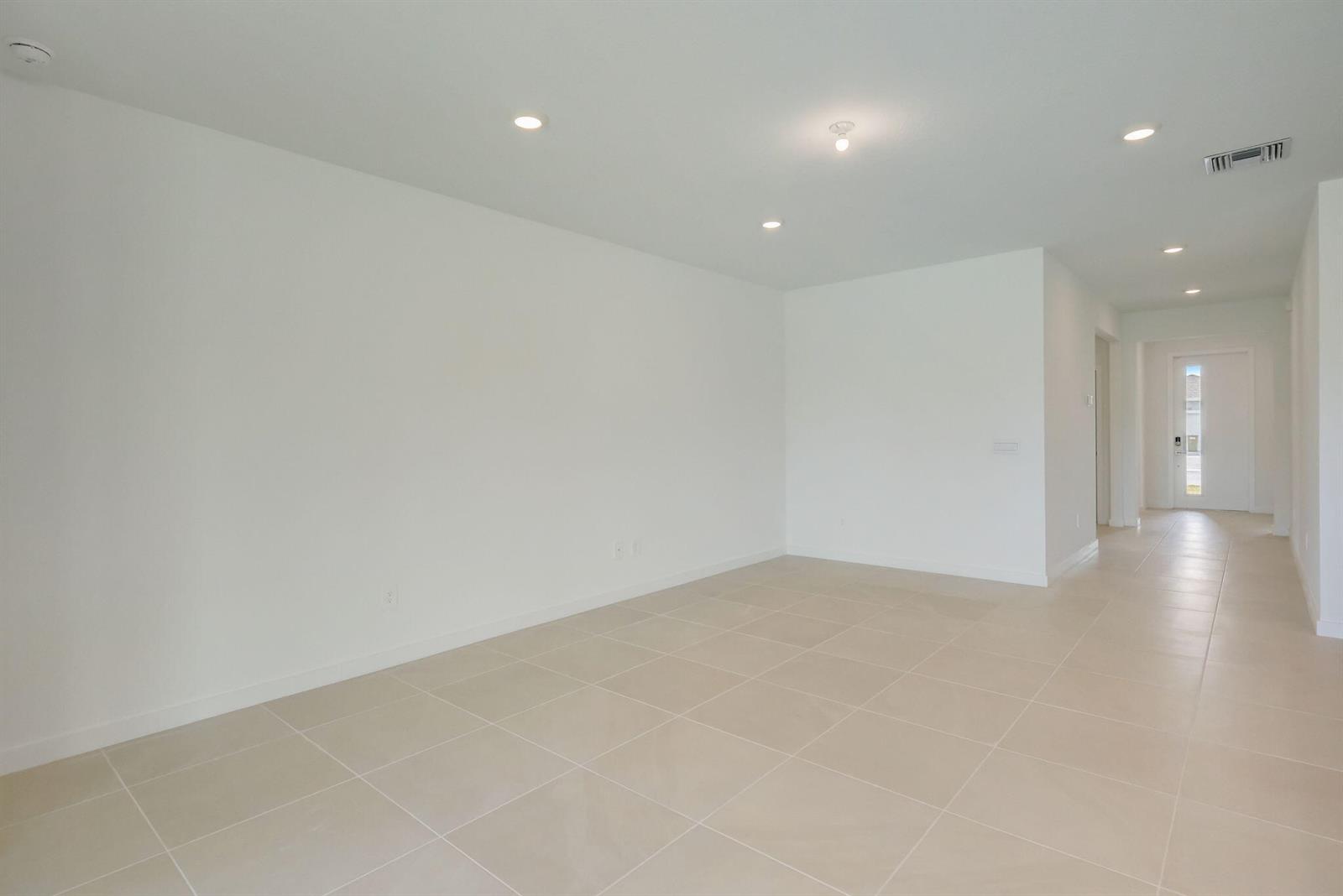 An empty room with white walls, recessed lighting, and light-colored tile flooring — 5946 SE Skyblue Circle, Stuart FL 34997, STUART, FL