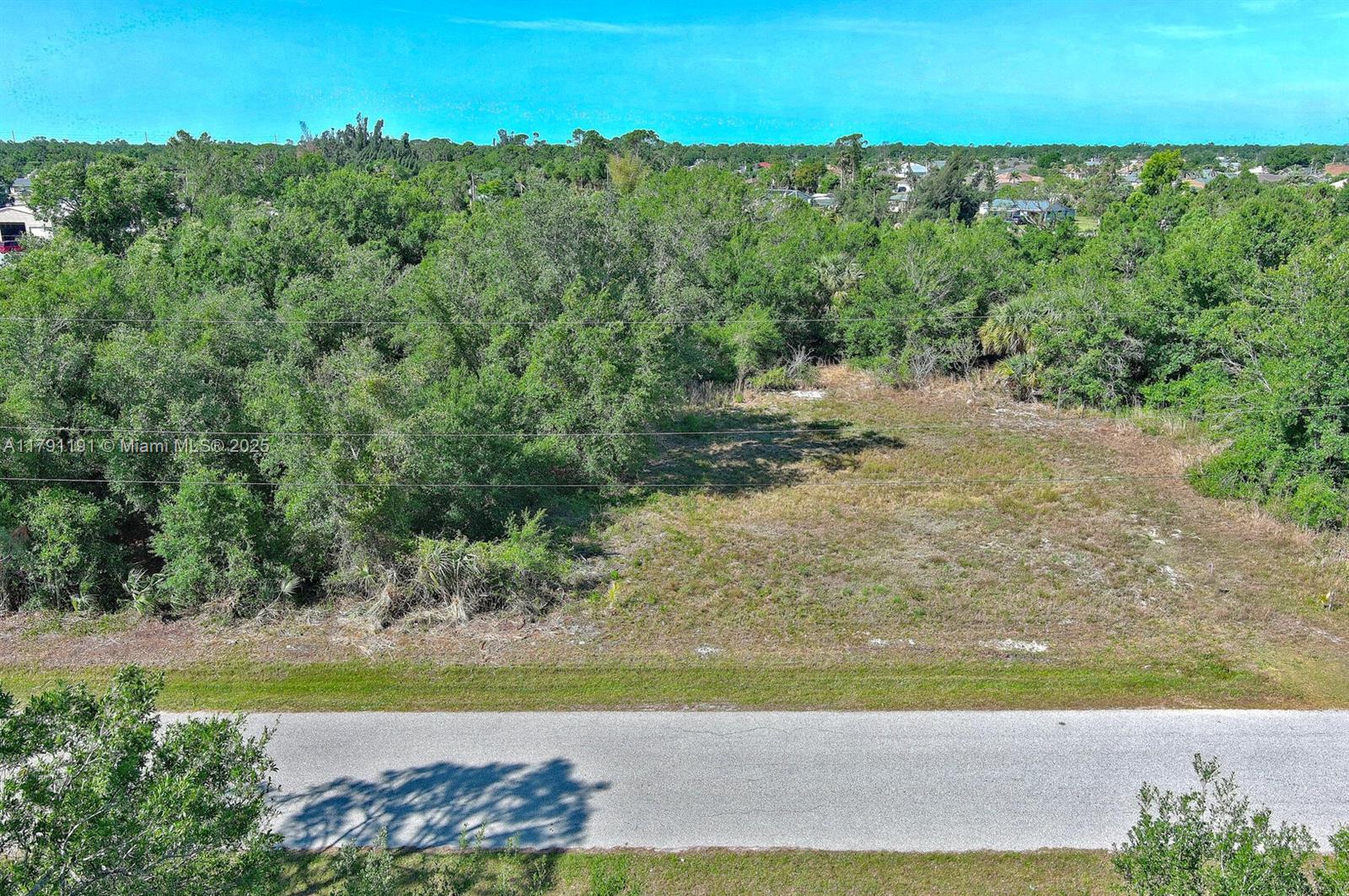 An aerial view shows a vacant, partially wooded lot adjacent to a paved road — 11117 1st Ave, Punta Gorda FL 33955, PUNTA GORDA, FL
