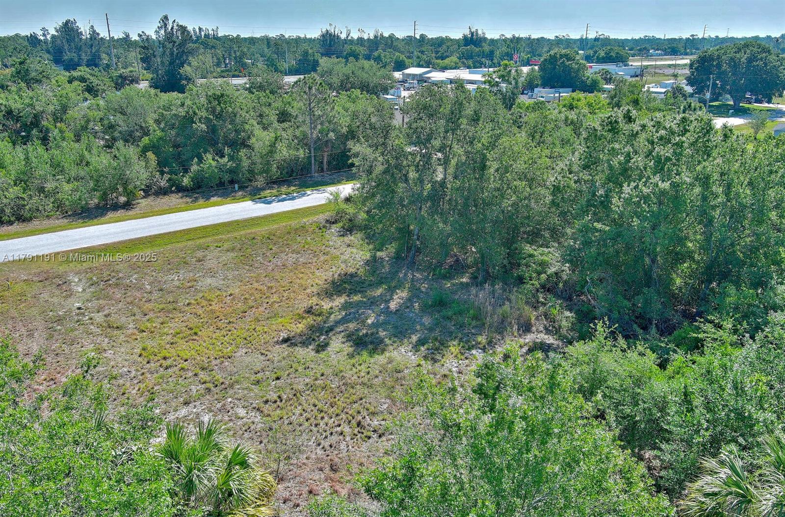 An aerial view shows a grassy, partially wooded lot adjacent to a paved road — 11117 1st Ave, Punta Gorda FL 33955, PUNTA GORDA, FL