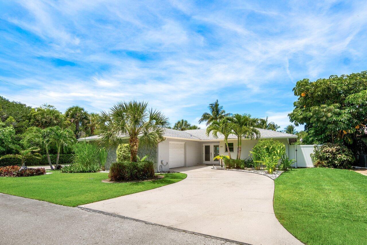 A single-story house with a concrete driveway, palm trees, and a manicured lawn — 106 Periwinkle Drive, Hypoluxo FL 33462, HYPOLUXO, FL