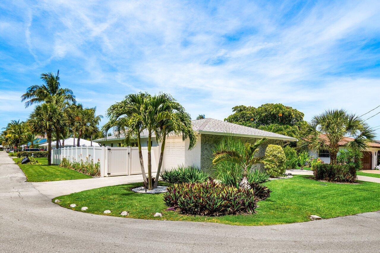 A single-story house with a white fence, palm trees, and a green lawn — 106 Periwinkle Drive, Hypoluxo FL 33462, HYPOLUXO, FL