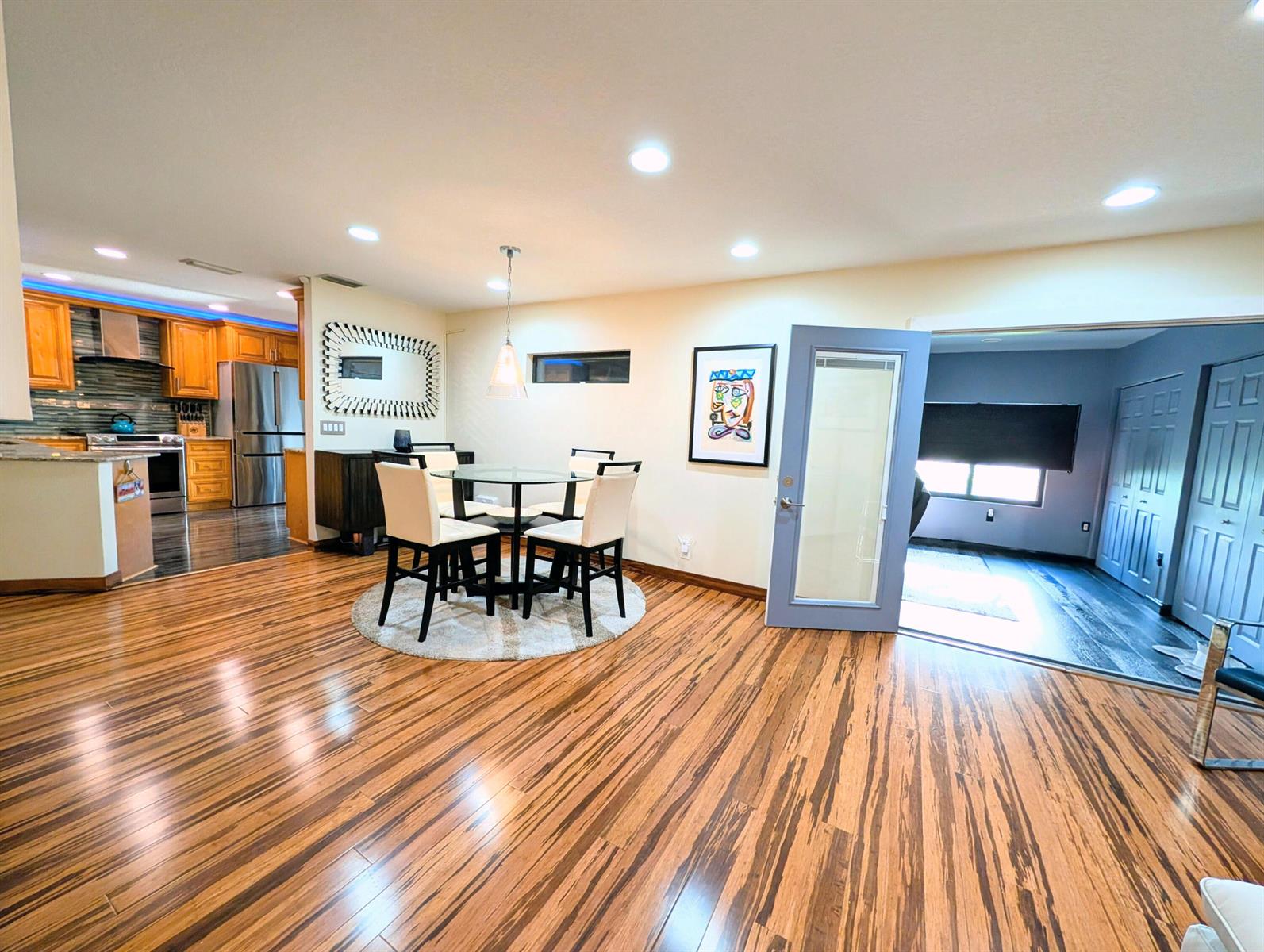 A dining area with a glass table and chairs sits on wood flooring near a kitchen — 5843 Northpointe Lane, Boynton Beach FL 33437, BOYNTON BEACH, FL