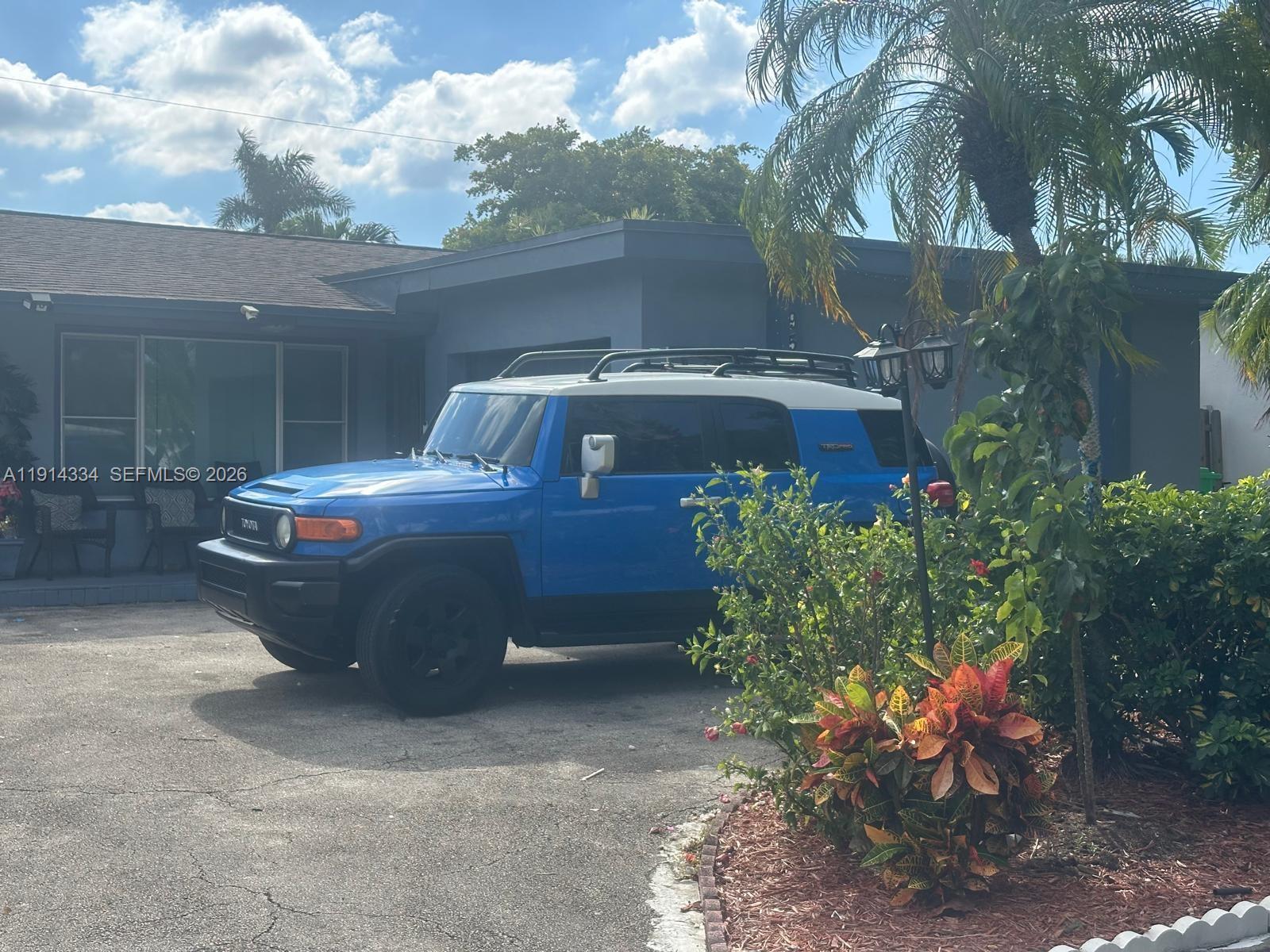 A blue Toyota FJ Cruiser is parked in the driveway of a single-story house — 9530 Sunset Strip, Sunrise FL 33322, SUNRISE, FL