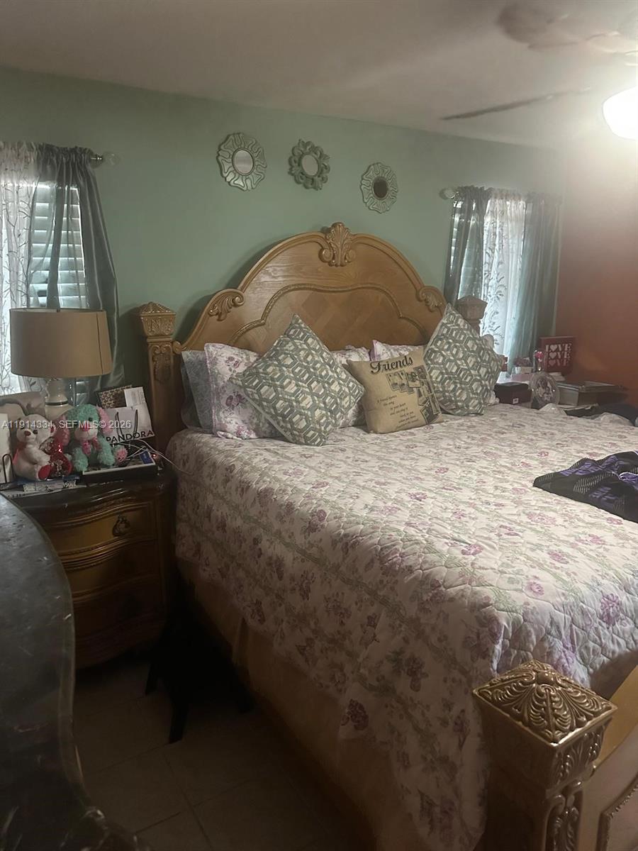 A bedroom features a large wooden headboard, floral bedding, and three decorative wall mirrors — 9530 Sunset Strip, Sunrise FL 33322, SUNRISE, FL