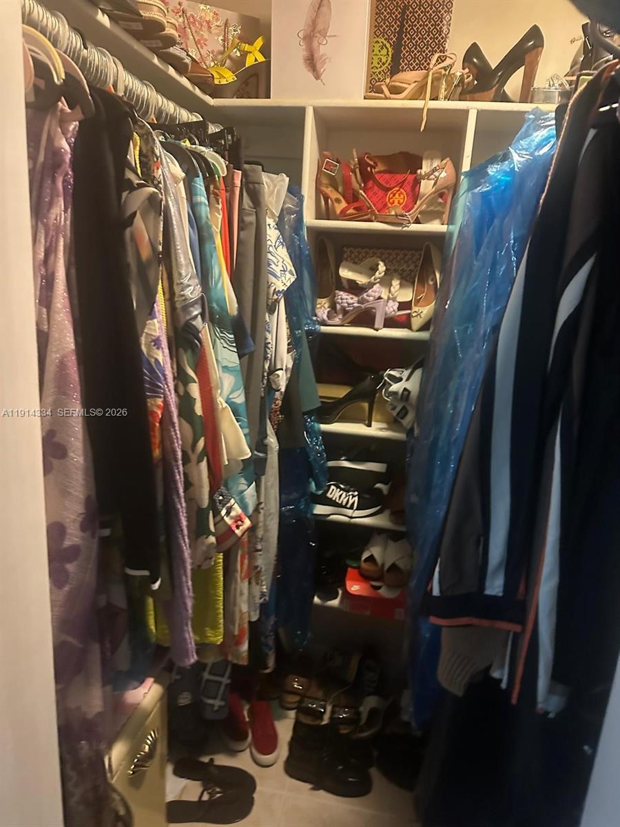 A walk-in closet features hanging clothes on both sides and open shelving for shoes — 9530 Sunset Strip, Sunrise FL 33322, SUNRISE, FL