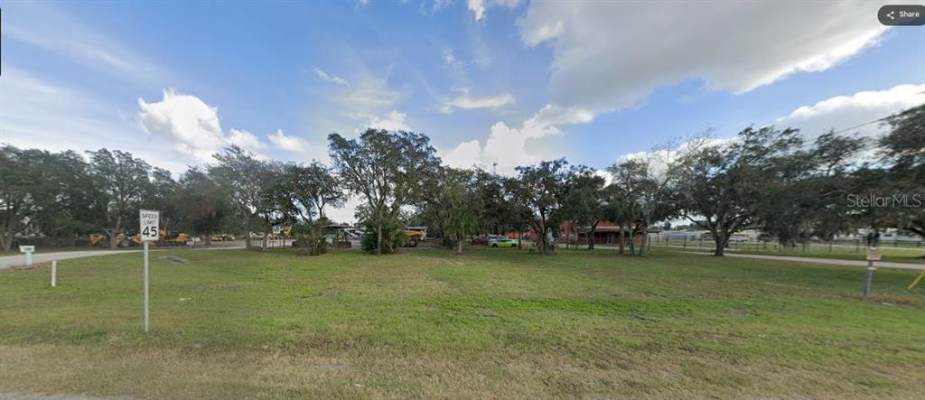 A grassy vacant lot with scattered trees and a speed limit sign under a cloudy sky — N/A, POLK CITY, FL