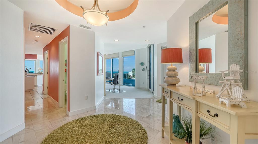 A bright foyer features a tiled floor, a round rug, and a console table — 4561 GULF OF MEXICO DRIVE UNIT 202, LONGBOAT KEY, FL