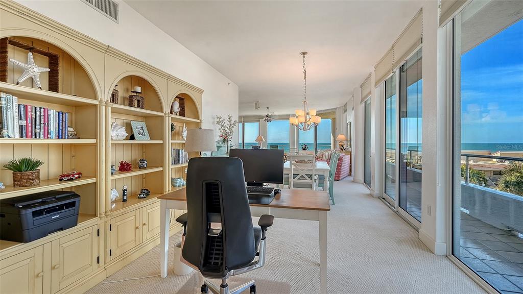 A home office with a desk and built-in shelving overlooks the ocean through large windows — 4561 GULF OF MEXICO DRIVE UNIT 202, LONGBOAT KEY, FL