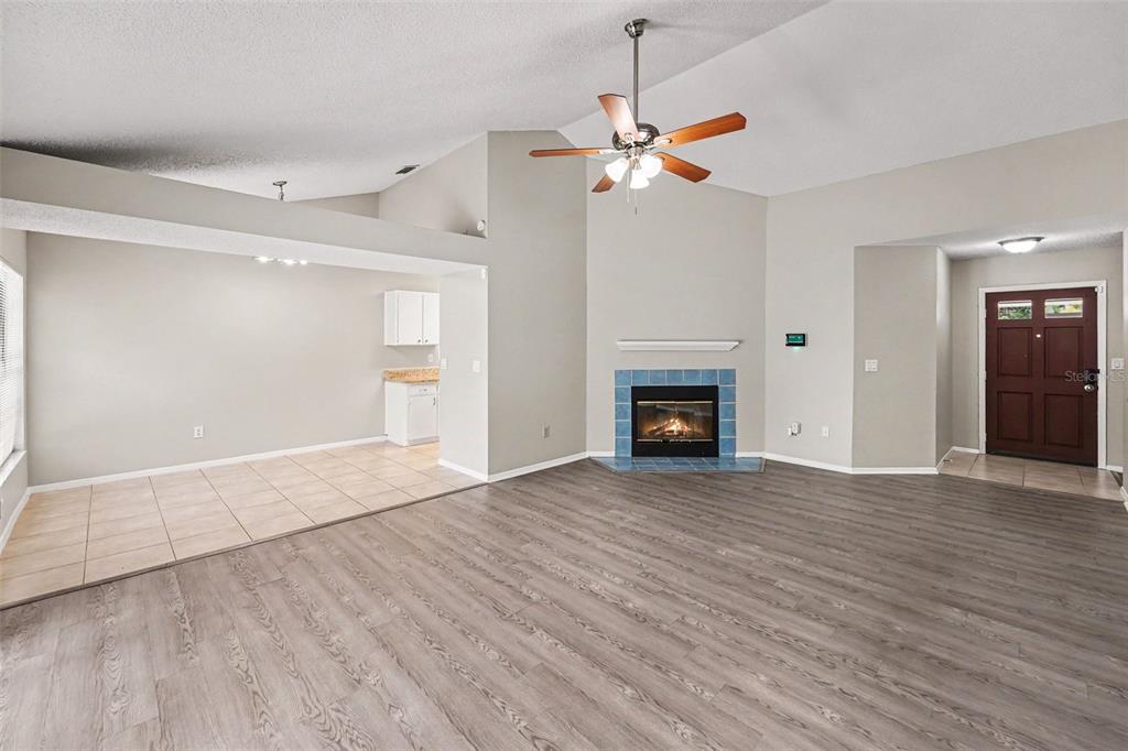 A living room with wood-look flooring, a tiled fireplace, and an adjacent tiled dining area — 8739 OSAGE DRIVE, TAMPA, FL