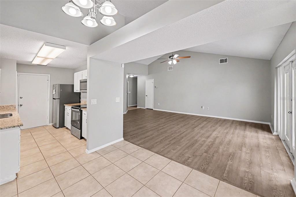 An open-concept kitchen with tile flooring transitions into a living area with wood-look flooring — 8739 OSAGE DRIVE, TAMPA, FL