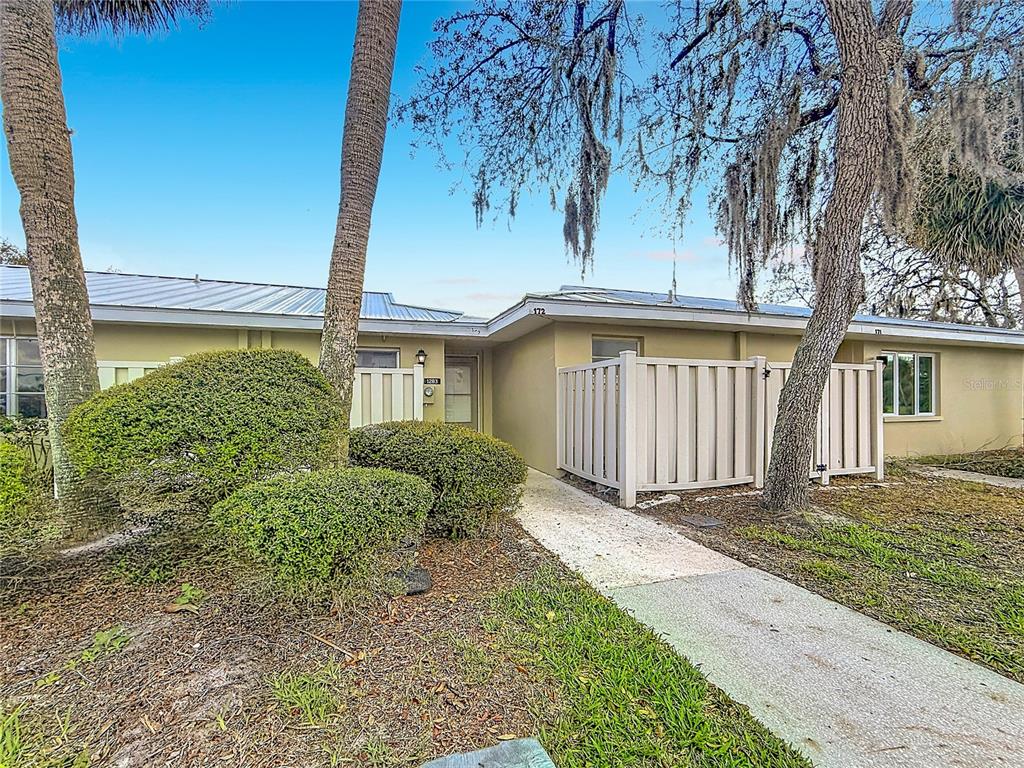 A single-story building exterior features a concrete walkway leading to a recessed front entrance — 1283 N OSPREY POINT UNIT 172, CRYSTAL RIVER, FL