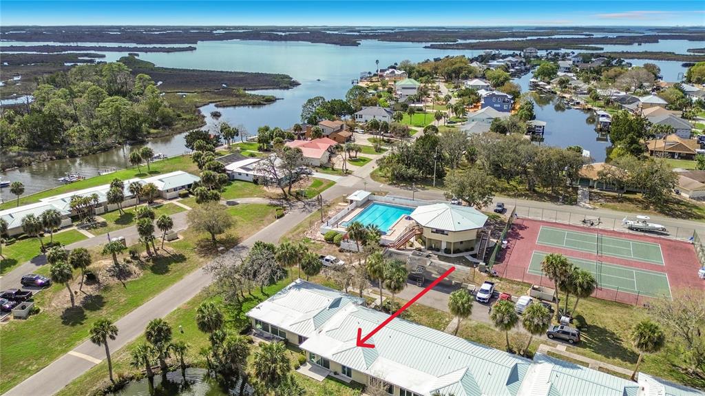 An aerial view shows a residential complex with a swimming pool, tennis courts, and water — 1283 N OSPREY POINT UNIT 172, CRYSTAL RIVER, FL
