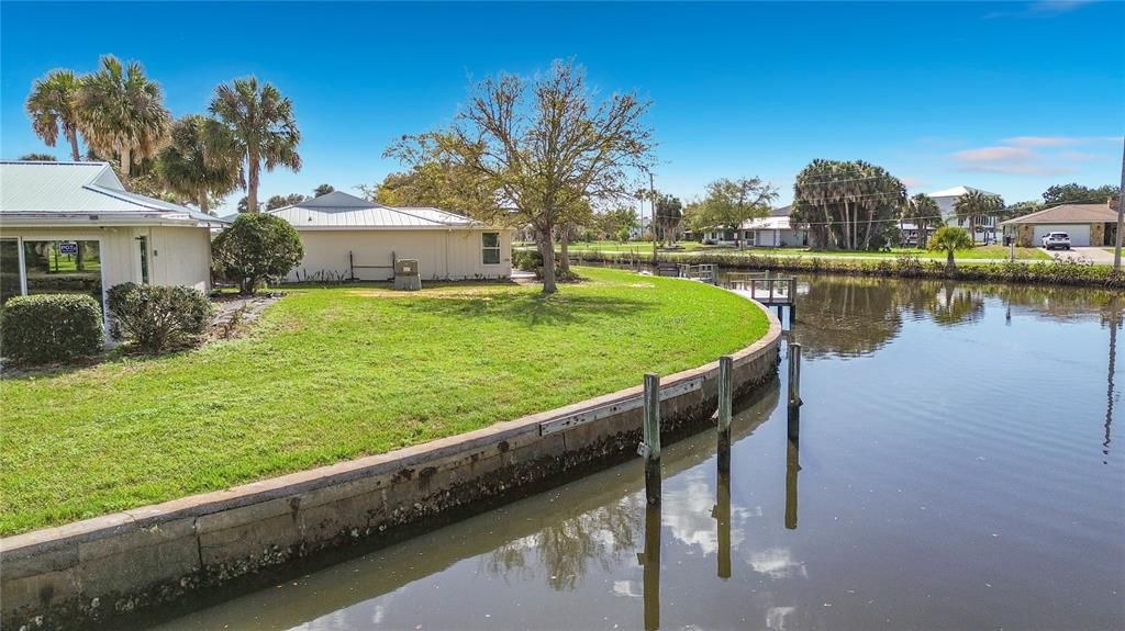 A grassy yard borders a canal with a concrete seawall and wooden pilings — 1283 N OSPREY POINT UNIT 172, CRYSTAL RIVER, FL