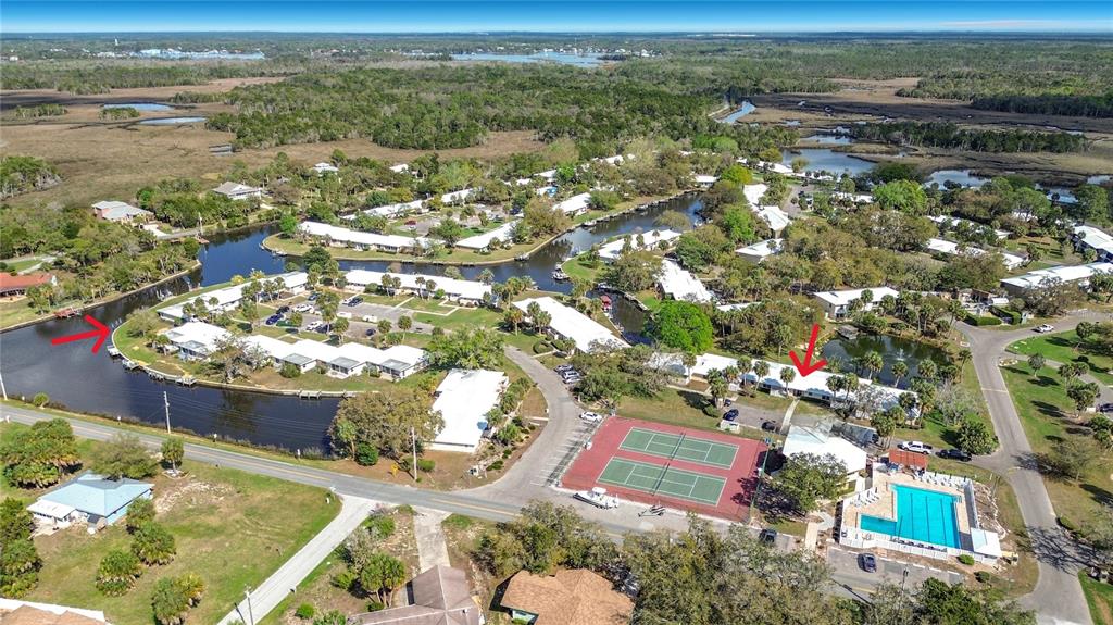 An aerial view shows a residential complex with a tennis court, swimming pool, and canals — 1283 N OSPREY POINT UNIT 172, CRYSTAL RIVER, FL