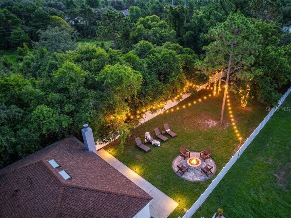 An aerial view of a backyard featuring a fire pit, lounge chairs, and string lights — 4020 STONEFIELD DRIVE, ORLANDO, FL