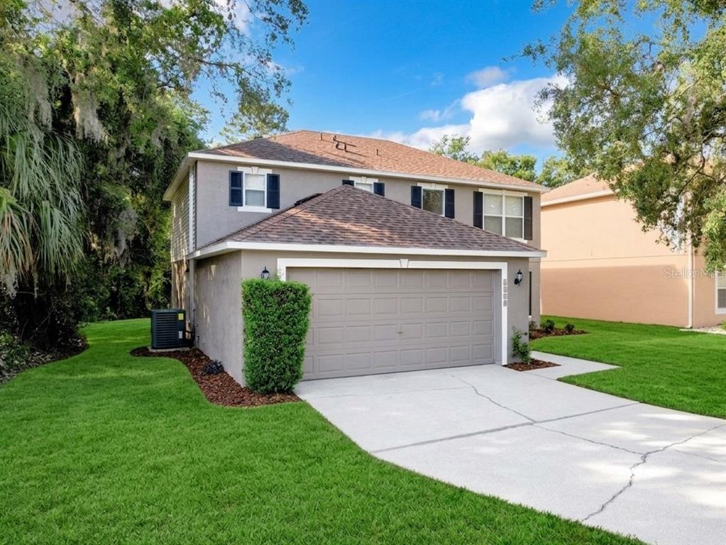 A two-story house with a gray stucco exterior, a two-car garage, and a green lawn — 4020 STONEFIELD DRIVE, ORLANDO, FL
