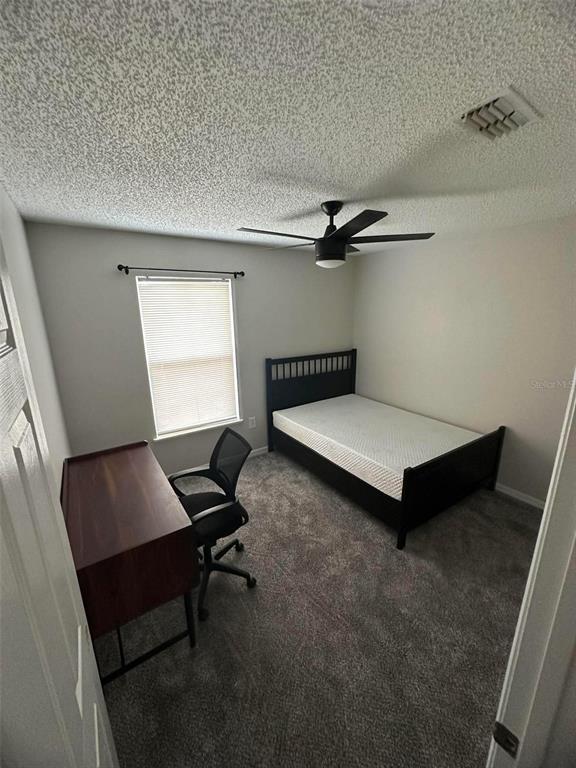 A bedroom features gray carpeting, a dark wood bed frame, and a matching desk — 4020 STONEFIELD DRIVE, ORLANDO, FL