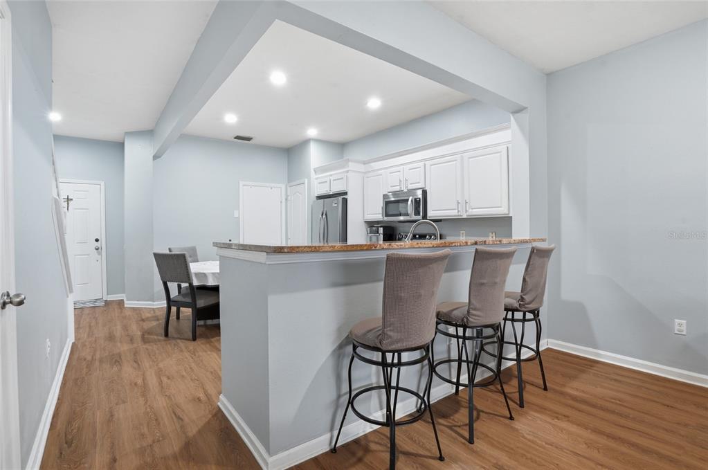 An entryway features a white door with a cross, a storage bench, and wood flooring — 26611 CHIMNEY SPIRE LANE, WESLEY CHAPEL, FL