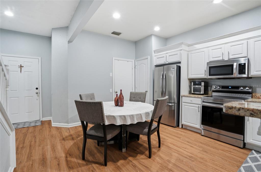A kitchen with white cabinets, stainless steel appliances, and a dining table with four chairs — 26611 CHIMNEY SPIRE LANE, WESLEY CHAPEL, FL