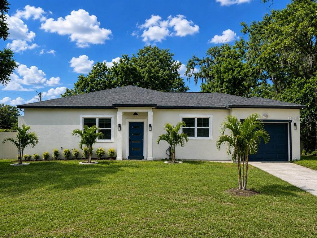 A single-story house with a white stucco exterior, blue door, and a gray shingled roof — 108 MISSION HILLS AVENUE, TAMPA, FL
