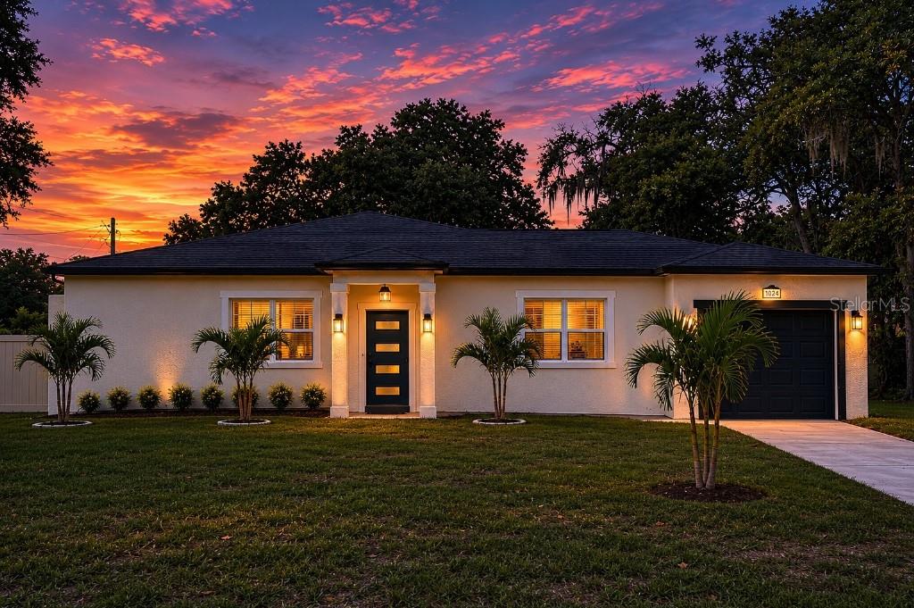 A single-story house with a dark front door and garage at sunset — 108 MISSION HILLS AVENUE, TAMPA, FL