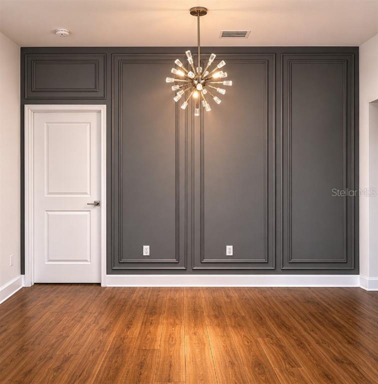 A dining room features dark gray paneled walls, a modern sputnik chandelier, and wood flooring — 108 MISSION HILLS AVENUE, TAMPA, FL