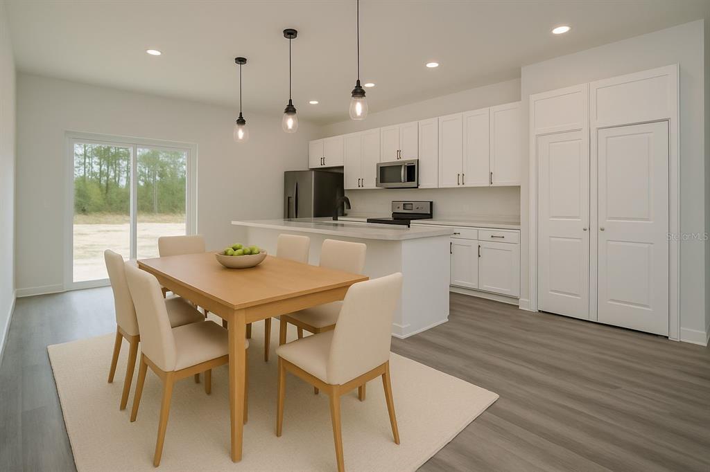 A dining area and kitchen with white cabinets, a central island, and light wood flooring — 2580 GALLARDIA DRIVE, INDIAN LAKE ESTATES, FL