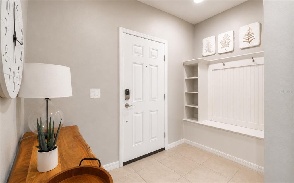An entryway features a white door, a built-in bench with shelving, and a wooden console table — 886 PARADISE DRIVE, DAVENPORT, FL
