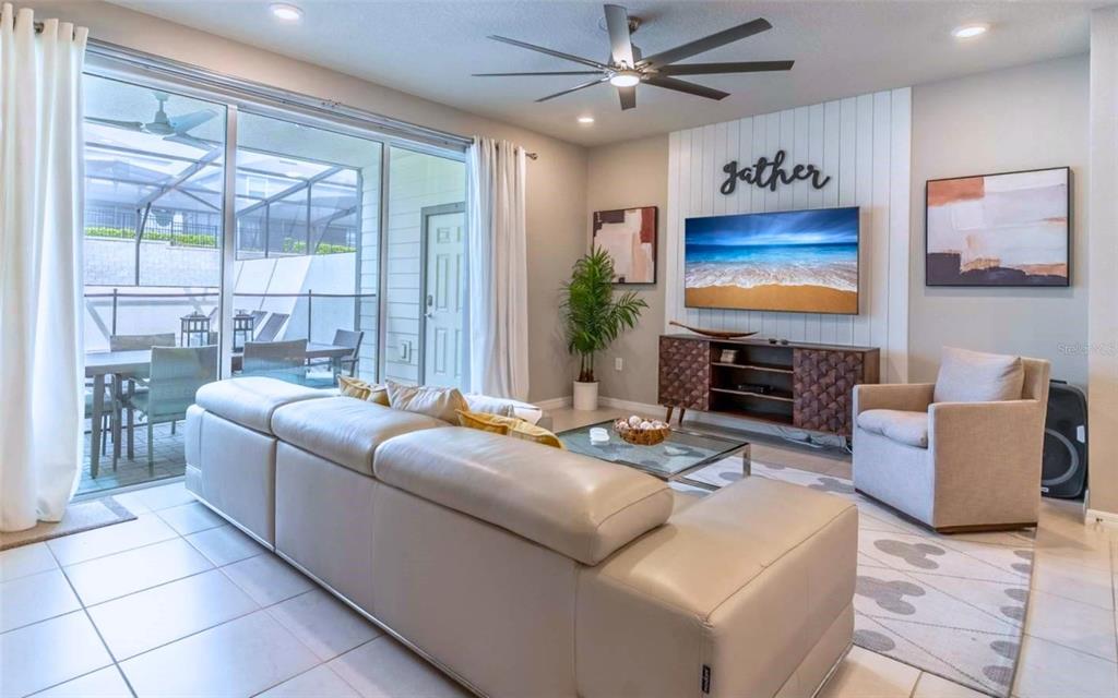 A living room features a beige sectional sofa, a television on a wood console, and sliding doors — 886 PARADISE DRIVE, DAVENPORT, FL