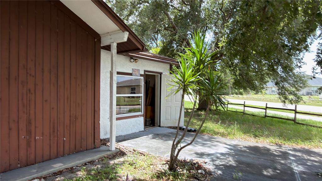 A view of a house exterior with a concrete patio, a doorway, and a window — 621 ELDRON BOULEVARD SE, PALM BAY, FL