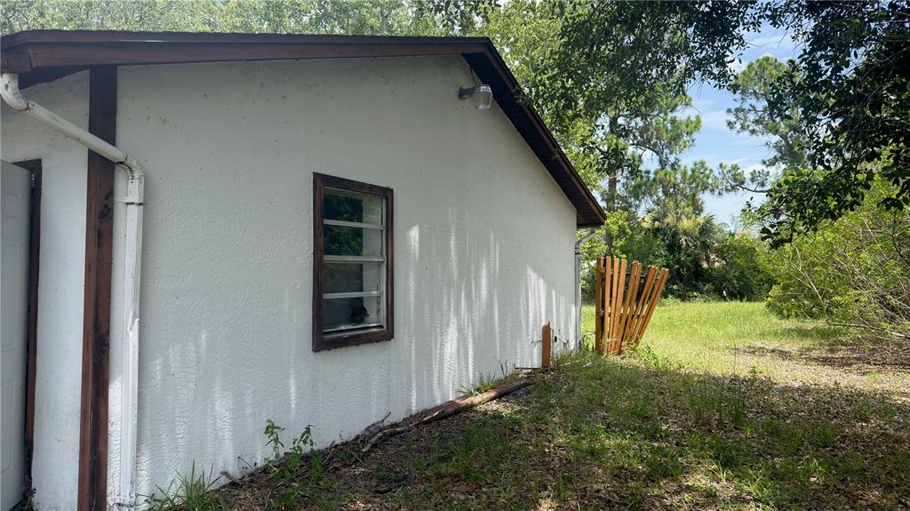 The exterior side of a white stucco building features a window and a downspout — 621 ELDRON BOULEVARD SE, PALM BAY, FL