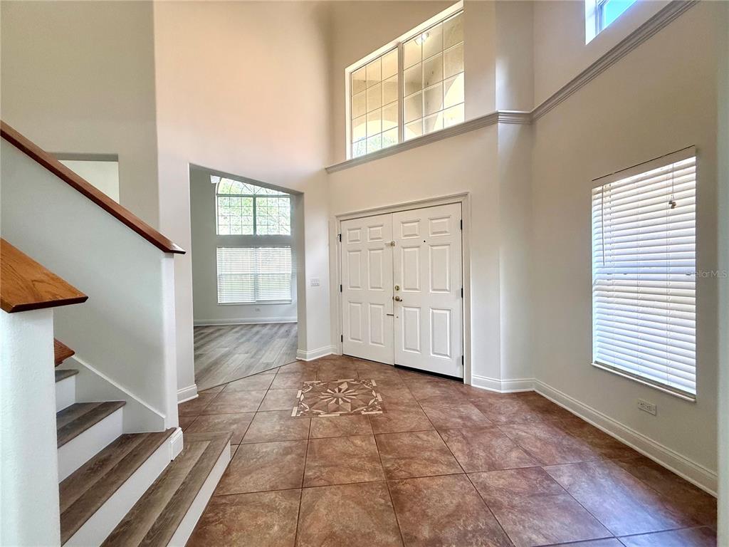 A two-story foyer features tile flooring, a staircase with wood accents, and double front doors — 6984 BRESCIA WAY, ORLANDO, FL