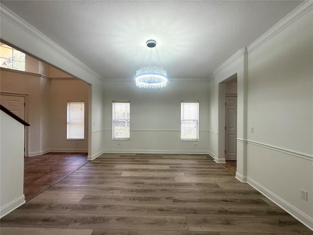 A dining room features light wood-look flooring, white walls with chair rail molding, and a chandelier — 6984 BRESCIA WAY, ORLANDO, FL