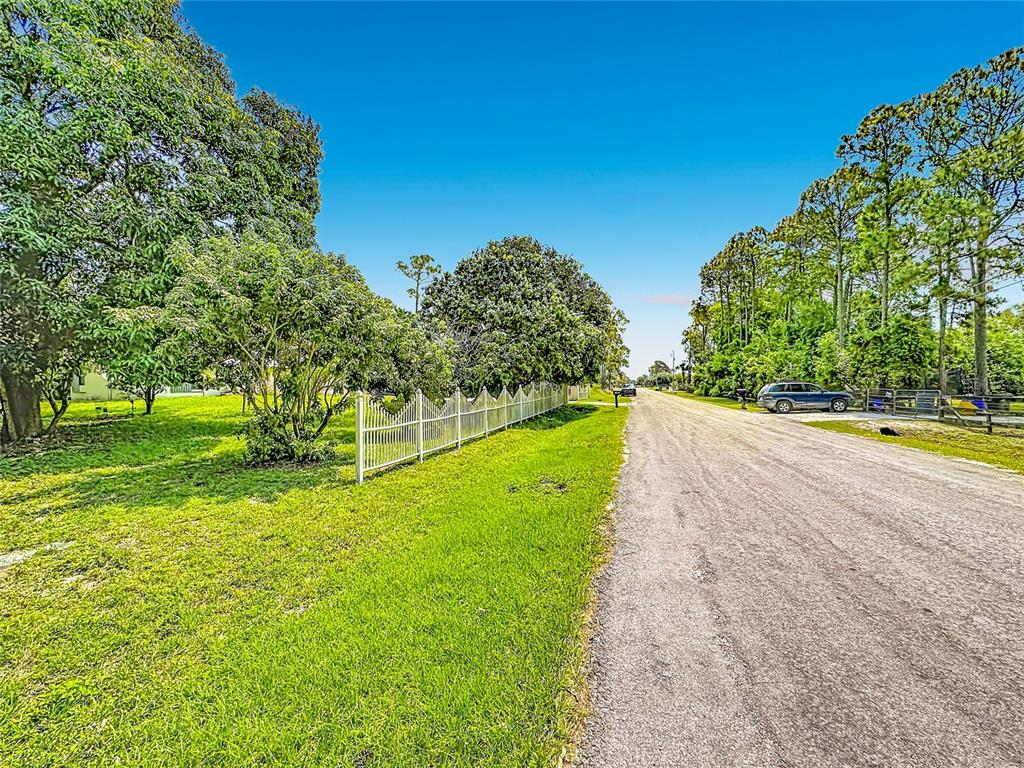 A gravel road runs alongside a grassy lot enclosed by a white picket fence — 12821 86TH ROAD N, WEST PALM BEACH, FL