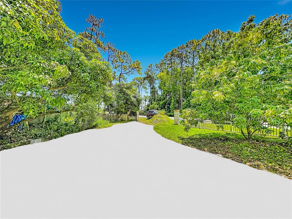 A paved driveway leads toward a gated entrance surrounded by lush trees and greenery — 12821 86TH ROAD N, WEST PALM BEACH, FL