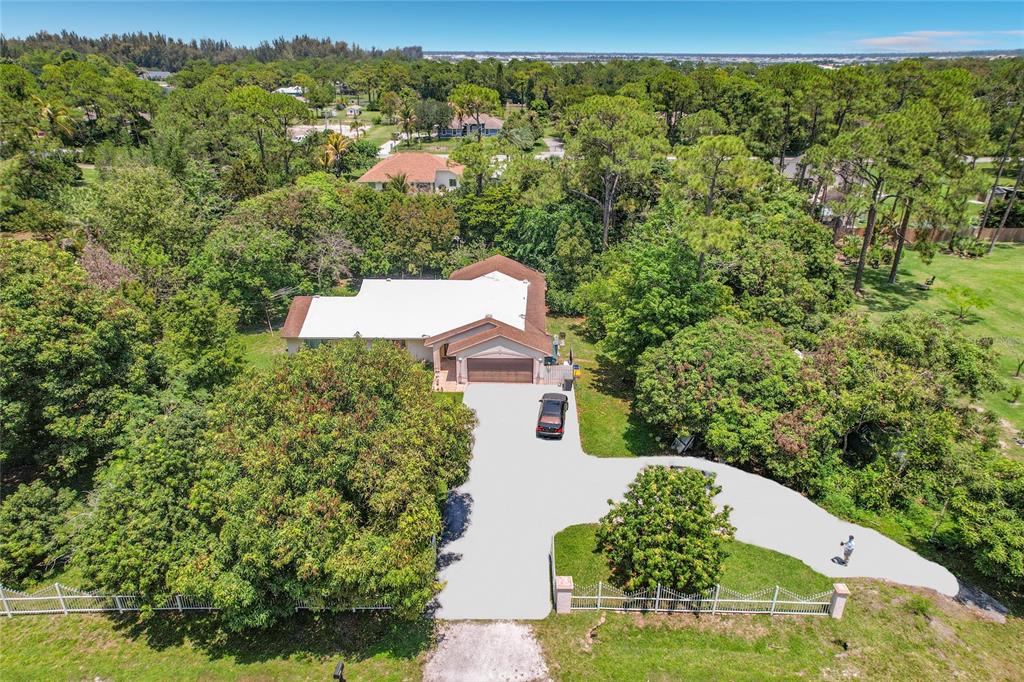 An aerial view shows a single-story house with a large driveway surrounded by dense trees — 12821 86TH ROAD N, WEST PALM BEACH, FL